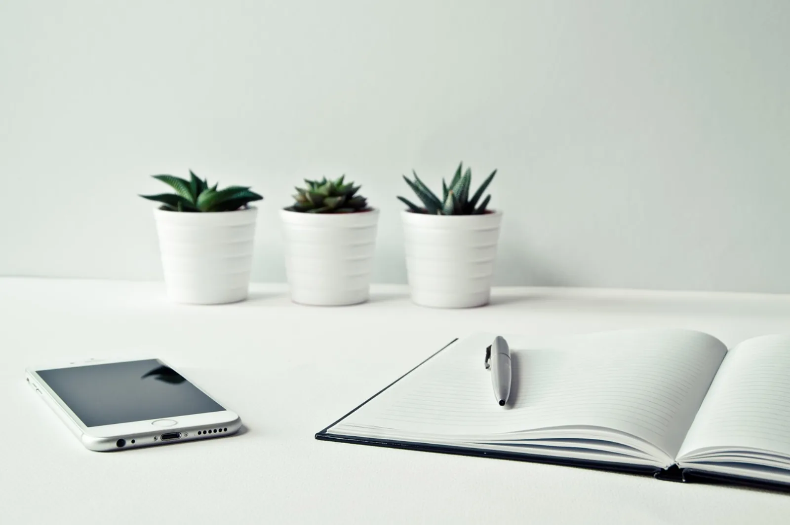 Aufgeräumter Schreibtisch mit Smartphone und Notizbuch – Helpdesk auslagern im Mittelstand