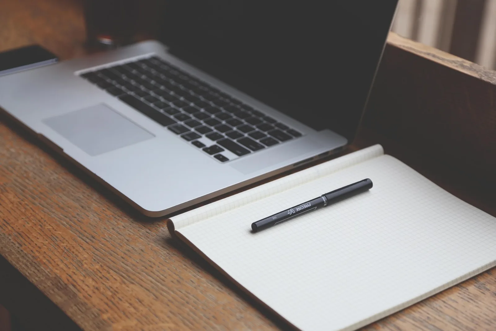 Vorbereiteter Arbeitsplatz mit Notebook und leerem Notizblock als Sinnbild für eine IT-Onboarding Checkliste